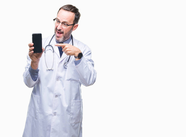 Mezza età anziano hoary medico uomo mostrando schermo smartphone su sfondo isolato molto felice puntando con mano e dito
 - Foto, immagini