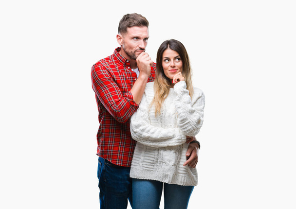 恋の冬のセーターを着ている若いカップルは、あごを考えて質問、物思いにふける式に手でバック グラウンドを分離しました。思いやりのある顔をして笑っています。疑いのコンセプト. - 写真・画像
