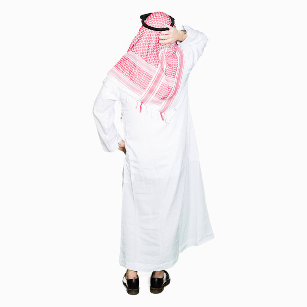 Arabe homme d'affaires avec les cheveux longs portant l'écharpe keffiyeh traditionnelle vers l'arrière en pensant au doute avec la main sur la tête
 - Photo, image