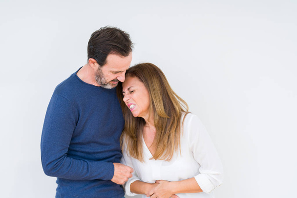 Beautiful middle age couple in love over isolated background with hand on stomach because nausea, painful disease feeling unwell. Ache concept. - Photo, Image