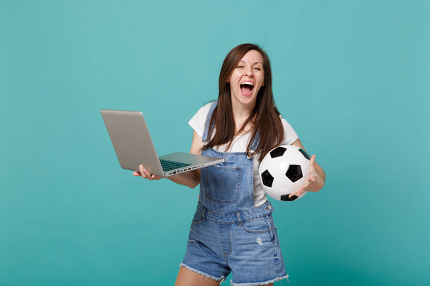 幸せな悲鳴少女サッカーファン青青緑色の背景に分離されたラップトップ pc コンピューターを使用してサッカー ボールを保持しています。人の感情、スポーツ家族レジャー ライフ スタイル コンセプト。コピー スペースをモックアップします。 - 写真・画像