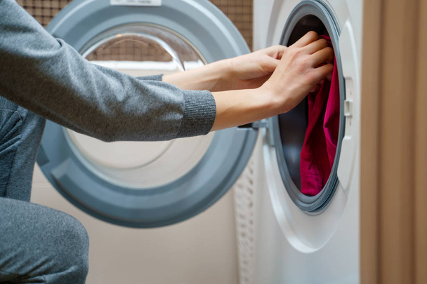Image of woman folding clothes into washing machine - Foto, Imagem