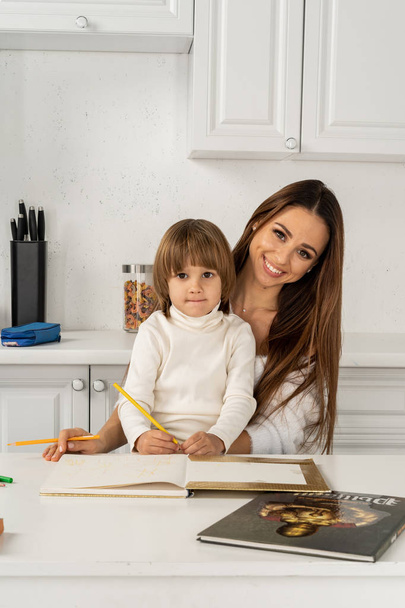 Nuori onnellinen äiti ja pieni poika piirustus värillisiä kyniä, poseeraa ja hymyilee
 - Valokuva, kuva