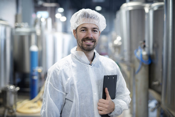 Portret uśmiechający się technolog w fabryce przemysłowej. - Zdjęcie, obraz