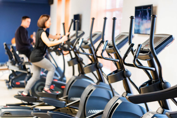 People train on elliptical cross trainers in fitness room - Photo, Image