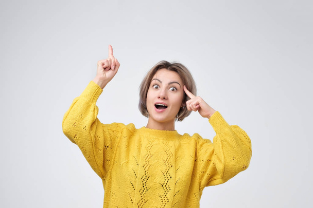 Young european girl in yellow sweater pointing with fingers up. - 写真・画像