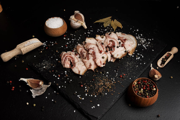 food composition with ham slices on cutting board surrounded by salt and pepper on table - Foto, Bild
