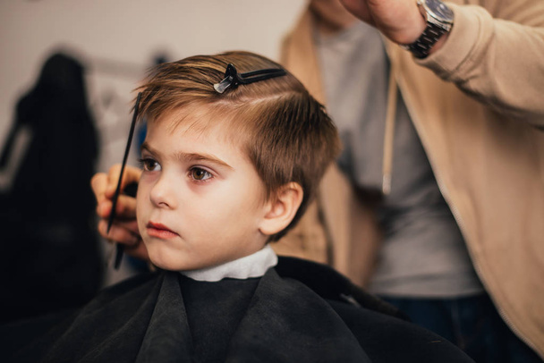 cropped image of barber making haircut of little boy at salon - Photo, image