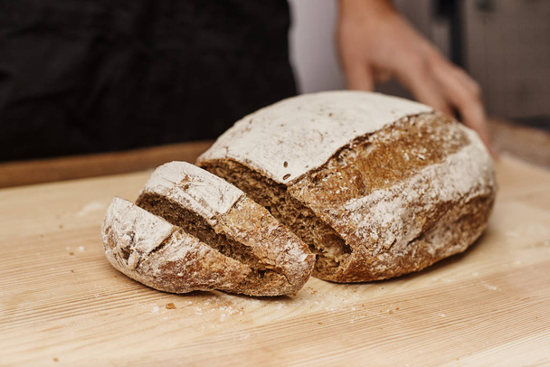 cropped shot of female baker cutting fresh baked bread by knife - Fotografie, Obrázek