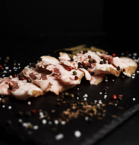 food composition with ham slices on cutting board surrounded by salt and pepper on table - Fotoğraf, Görsel
