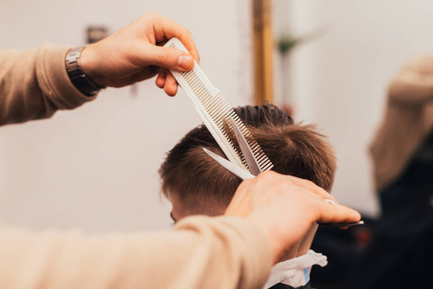 cropped image of barber making haircut of little boy at salon - Fotografie, Obrázek
