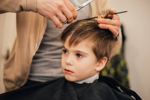cropped image of barber making haircut of little boy at salon - 写真・画像