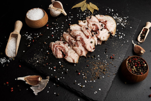 food composition with ham slices on cutting board surrounded by salt and pepper on table - Foto, Bild