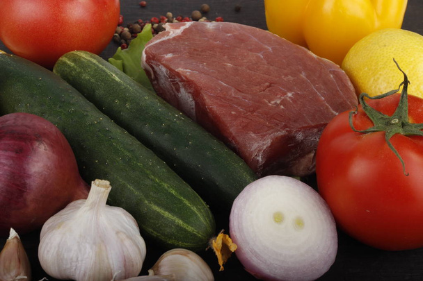 Closeup of meat with assorted vegetables over dark wooden background  - Foto, afbeelding