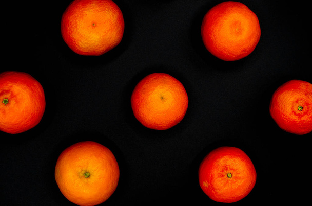 Mandarinas naranjas frescas formadas simétrica y fuertemente contrastando sobre un fondo negro
 - Foto, imagen