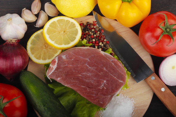 Closeup of meat with assorted vegetables over dark wooden background  - Foto, Imagem