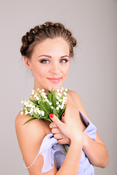 Young woman with beautiful hairstyle and flowers, on grey background - Fotoğraf, Görsel