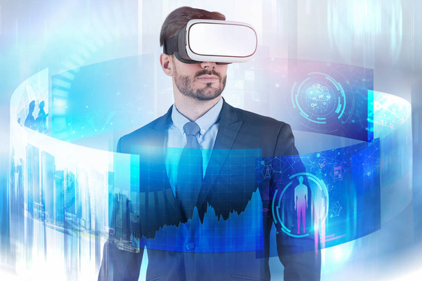 Bearded businessman in virtual reality goggles and suit looking at immersive business telecommunication interface. Toned image double exposure - Photo, image