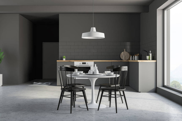 Innenraum der Küche mit grauen Wänden, Betonboden, grauen Arbeitsplatten und einem runden weißen Tisch mit schwarzen Stühlen. 3D-Darstellung - Foto, Bild