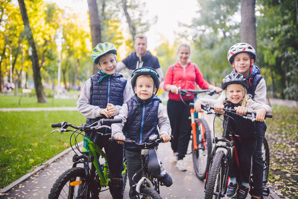 Theme family sports vacation in park in nature. big friendly Caucasian family of six people mountain bike riding in forest. Children brothers and sister stand on the background of parents in a row. - Zdjęcie, obraz
