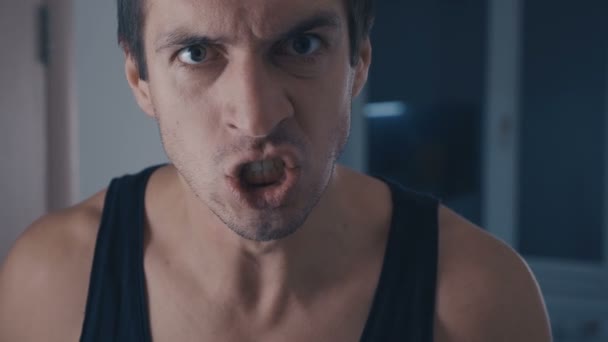 Closeup portret van agressieve man in vrouw-beater schreeuwen en bedreigend geweld thuis - Video