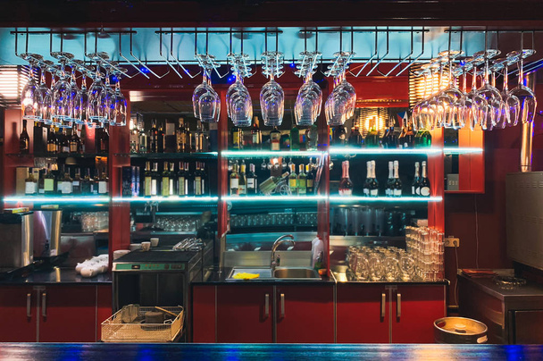 Photos of a stylish bar with colorful bright interior in the restaurant. Alcohol bars, bar counter, bartender's workplace. Empty the top of the wooden table with counter bar and bottles background - Photo, Image