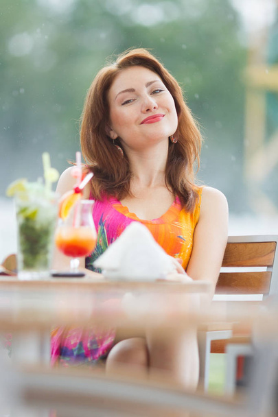 Beautiful young lady enjoying her fresh cocktail sitting in a restaurant outdoors - Foto, Imagen