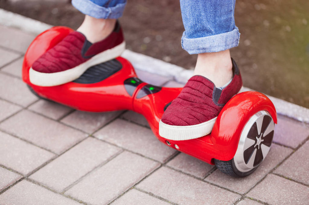  girl in shoes riding on modern red electric mini segway - Fotó, kép