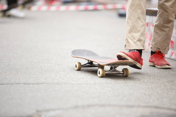 Skater boy rides on skateboard deck outdoor in summer day. Feet of young athlete riding on board during extreme summer sports competition - Foto, Imagem