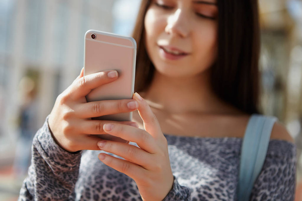 White brunette girl using modern smartphone. Huge silver phone model in her hands - Фото, зображення