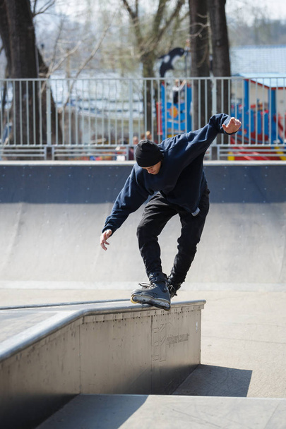 KIEV - 15 APRIL, 2018: Aggressive inline skate contest in outdoor skatepark. Young skater boy grinds on rail with roller blades. - Foto, afbeelding