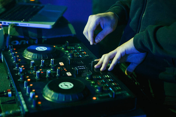 MOSCOW - 30 NOVEMBER,2016: Disc jockey mixing music on digital midi turntable controller at hip hop party on stage in night club. fingers of DJ mixing tracks on mixer on concert in nightclub - Photo, Image