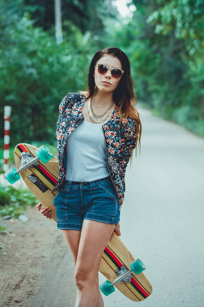 молода красива жінка зі скейтбордом у парку
 - Фото, зображення