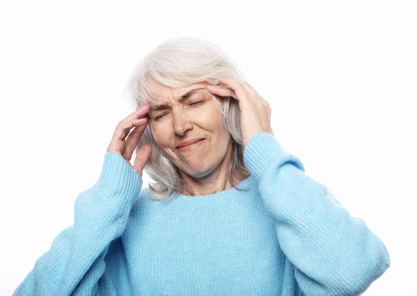 Lifestyle, health  and people concept: senior lady having headache over white background - Fotó, kép