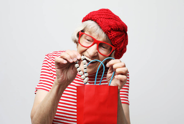 lifestyle  and people concept: elderly woman pulls out a gift from the bag - Foto, afbeelding