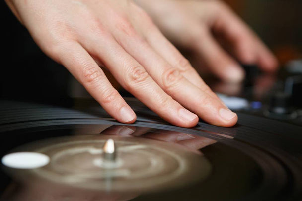 Djs hand scratch vinyl record on turn table.Professional night club turntables record player in focus.Party dj audio equipment setup.Play tracks,scratch records at night adult entertainment event - Fotó, kép
