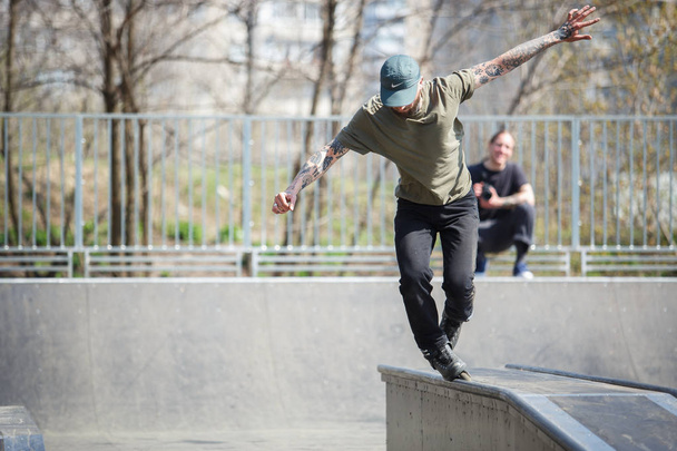 KIEV - 15 APRIL, 2018: Aggressive inline skate contest in outdoor skatepark. Young skater boy grinds on rail with roller blades. - Fotó, kép
