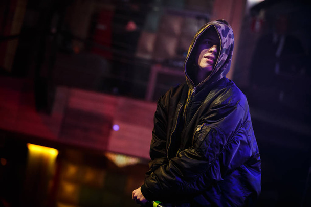 MOSCOW - 16 FEBRUARY, 2017: Young white Russian rap singer performs on stage in trendy camo hoodie coat. Rapper sings on scene in night club during music festival. Jazz Cartier hip hop party performer - 写真・画像