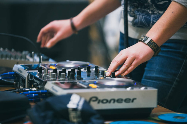 MOSCOW-9 JANUARY,2016: Young dj plays music set with digital Pioneer midi controller turn table device. Professional audio equipment on event stage. Disc jockey playing musical tracks with turntables - Photo, image