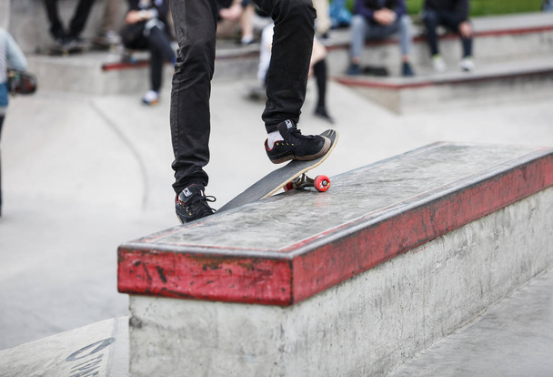 MOSCOW- 15 MAY,2016: Summer street skateboarding contest in outdoor skate park.Extreme skating in concrete skatepark outside.Skateboarder exercising.Active dynamic extremal sport.Young skater boy smith grind on ledge - Foto, Imagem