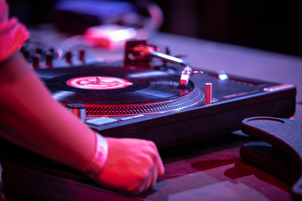 Club party dj plays music with turntables.Hands of hip hop disc jockey man scratching vinyl records on stage in nightclub.Professional audio equipment on scene.Retro turn table player and sound mixer - Foto, immagini