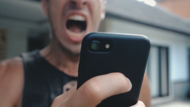 怒っている男スマートフォンを使用しています。男はスマートフォンで読んだメッセージに腹を立てている。怒りの男はスマートフォンを使う. - 映像、動画