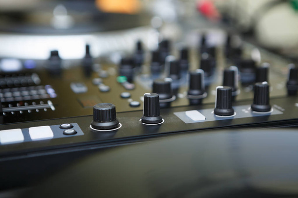 Top class dj audio mixer controller to play music and remix tracks at party in nightclub.Mixing controller knobs and faders in focus.Disc jockey setup for live event in night club - Foto, Imagem