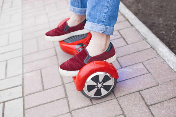 Close up on feet of a gir in marsala shoes riding on a modern red electric mini segway or hover board scooter. Trending new transportation technology that is so much fun and easy to ride and produces no air pollution to the atmosphere. - Fotografie, Obrázek