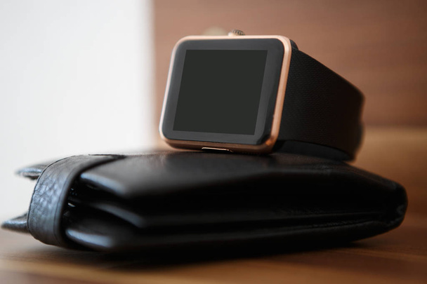 Stylish smart watches on black leather wallet.Business style gadget to stay always connected.Put mobile app logo or text on empty screen.Cool new device for wireless networks - Foto, immagini