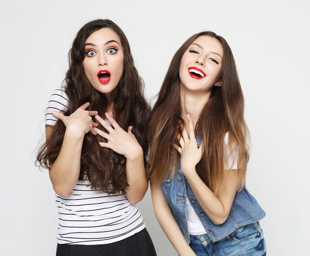 Two young girl friends having fun. Both making surprised faces. - Foto, afbeelding