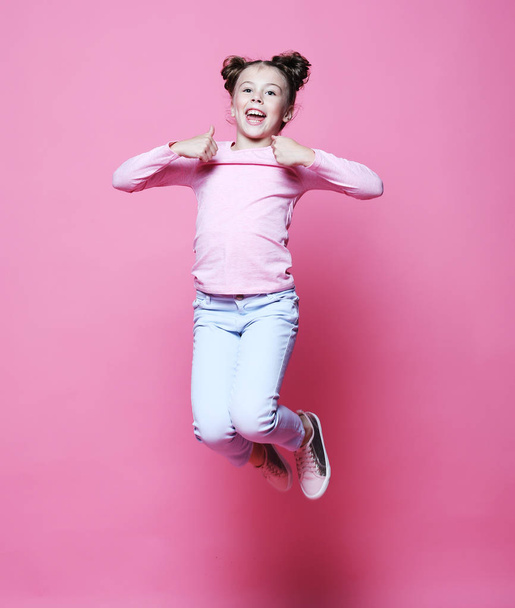  funny child girl dressed casual jumping on pink  background  - Φωτογραφία, εικόνα