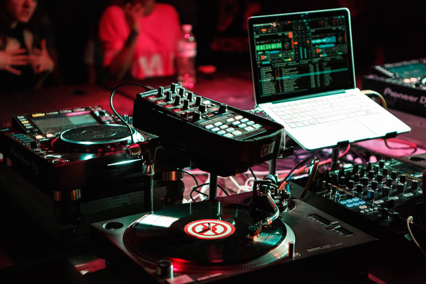KIEV-4 JULY,2018: Professional dj setup on concert stage.Retro Technics SL 1210 turntable player,Apple Macbook with Traktor software,Pioneer DJM sound mixer and midi controller on table in night club - Foto, imagen