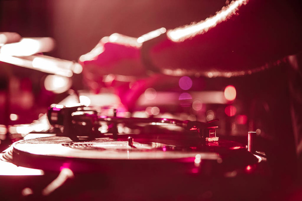 KIEV-4 JULY,2018: Dj plays music with retro Technics SL 1210 turntable on stage in night club. Rave party disc jockey playing musical set on scene in bright red lights - 写真・画像