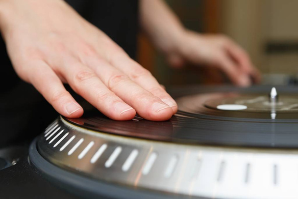 Disc jockey scratch vinyl record with music on turntable records player.Turntables vinyl disc in focus.Play music on dj audio equipment in night club.Close up,focus on djs hand on disc - Photo, image
